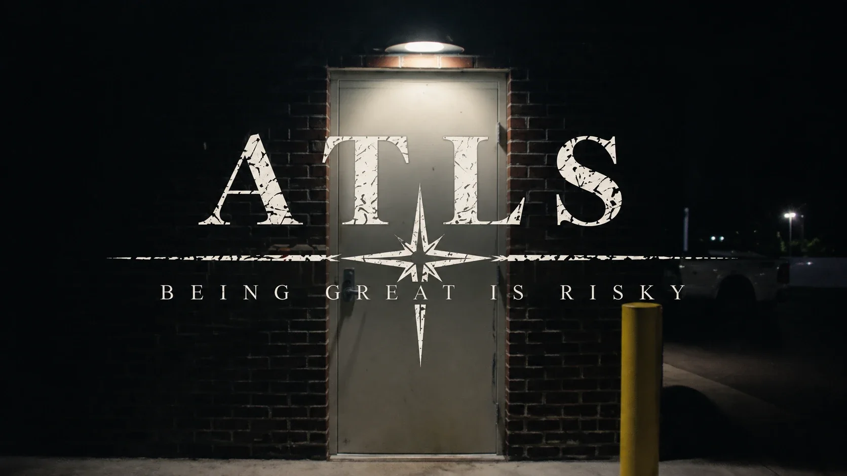 The ATLS wordmark and the words 'Being great is risky' over a steel door lit by a single lamp at night